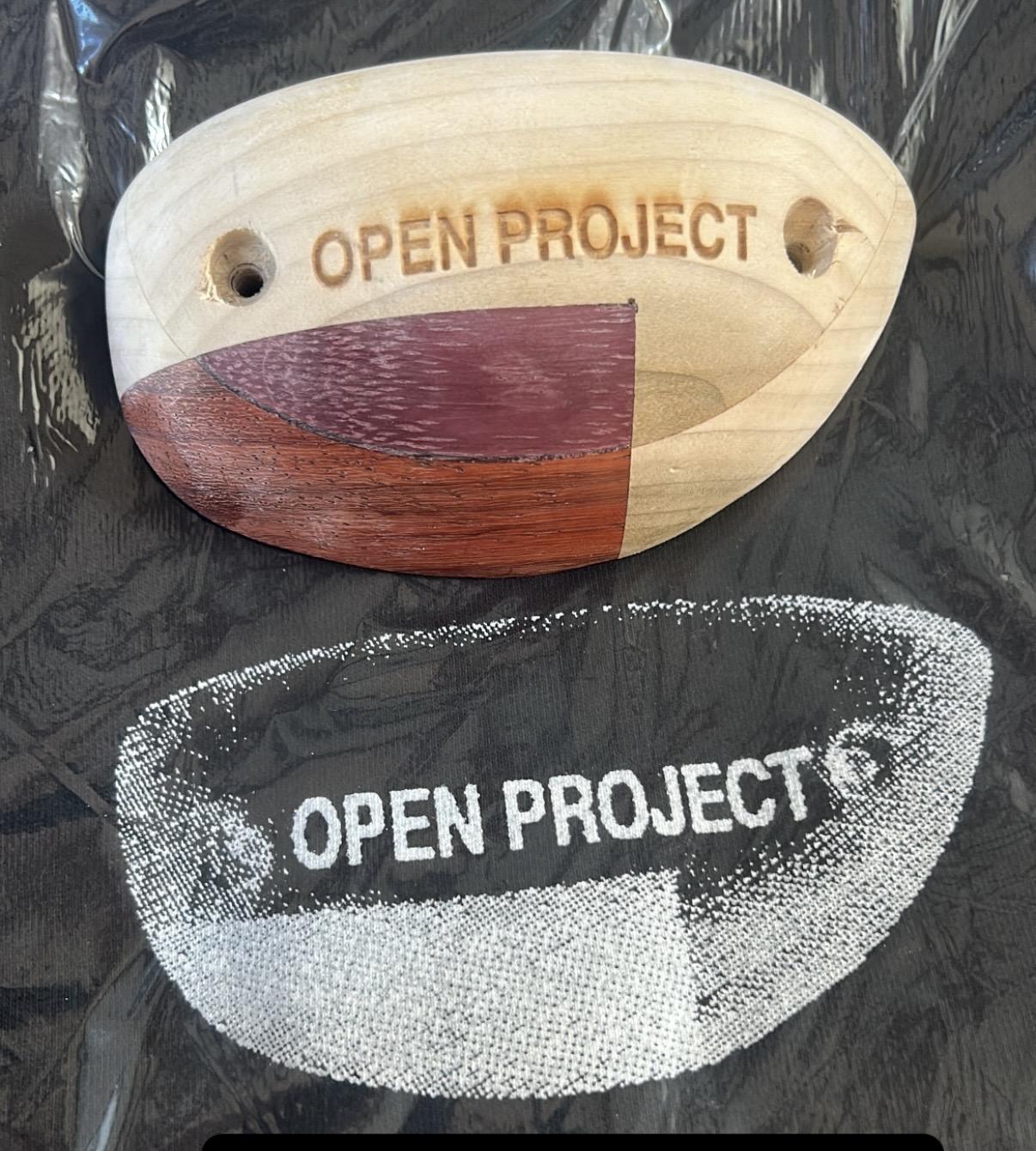 The Open Project logo on a wooden climbing hold, next to the same graphic screen printed using halftone dots